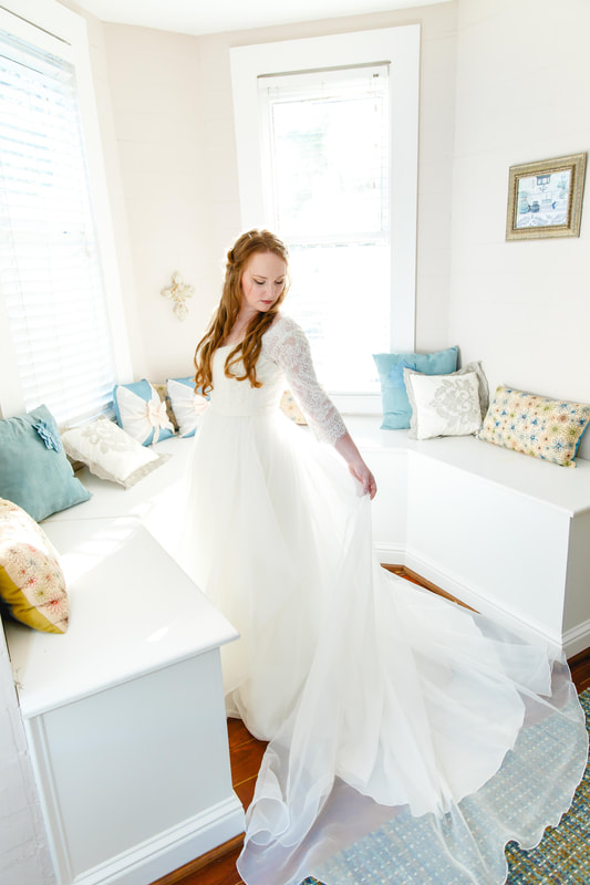 Bride showing off wedding dress in bedroom