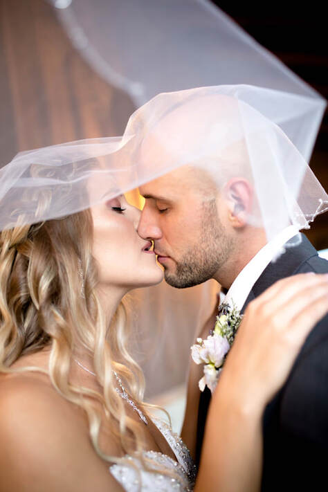 Bride and groom kissing under veil 
